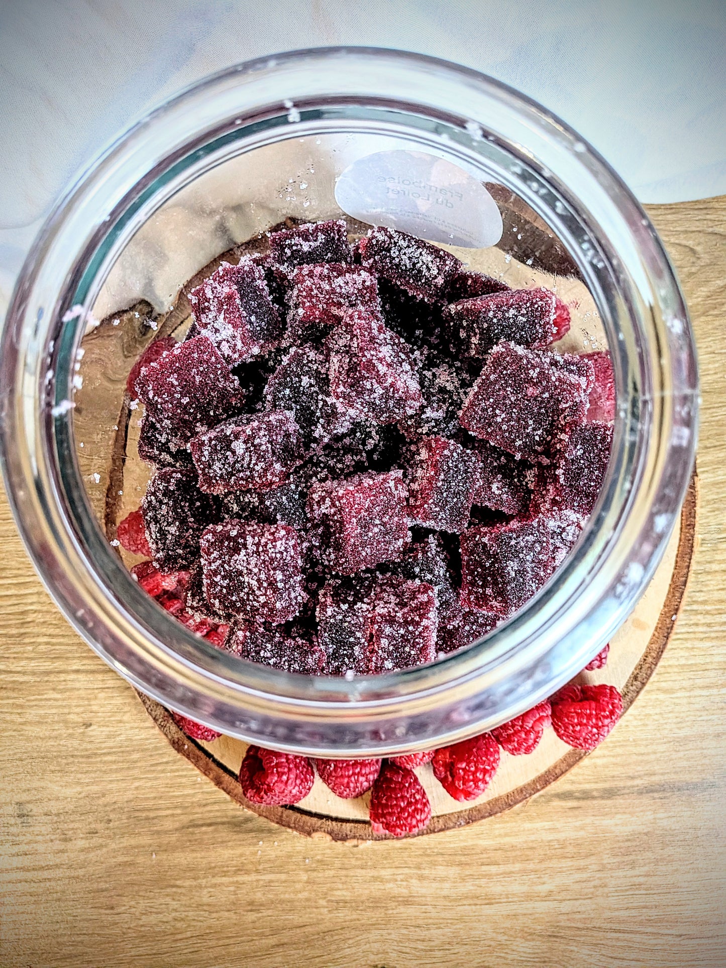 Vue de dessus d'un bocal ouvert rempli de pâtes de fruits à la framboise saupoudrées de sucre